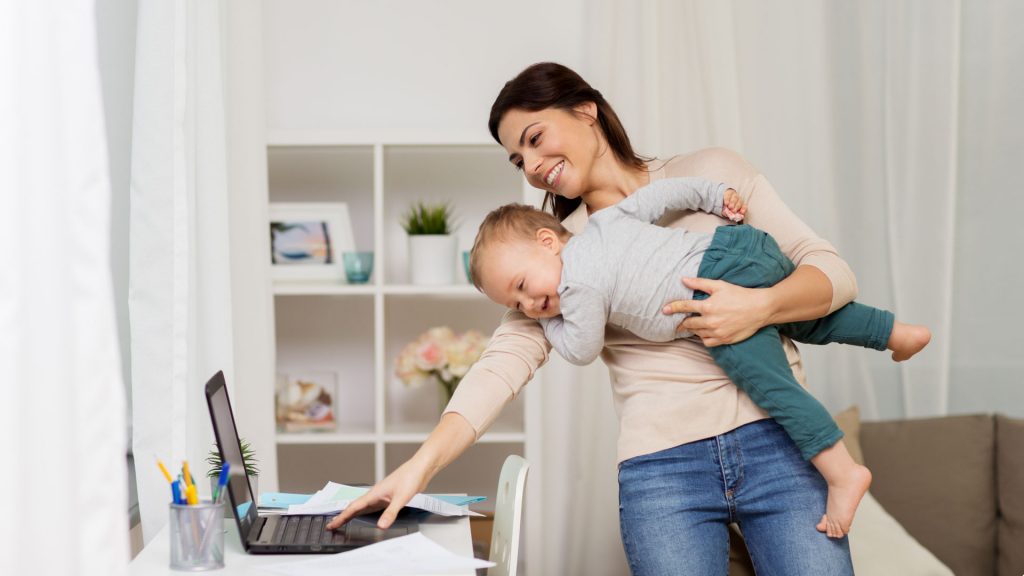 Working from home on laptop while holding your child