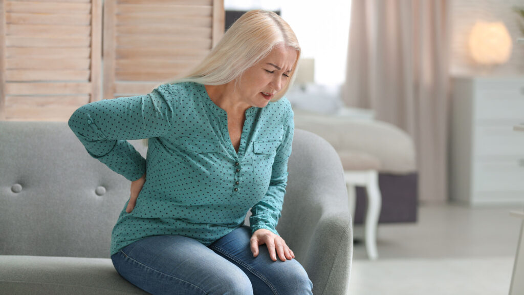 Woman suffering from acute back pain on couch