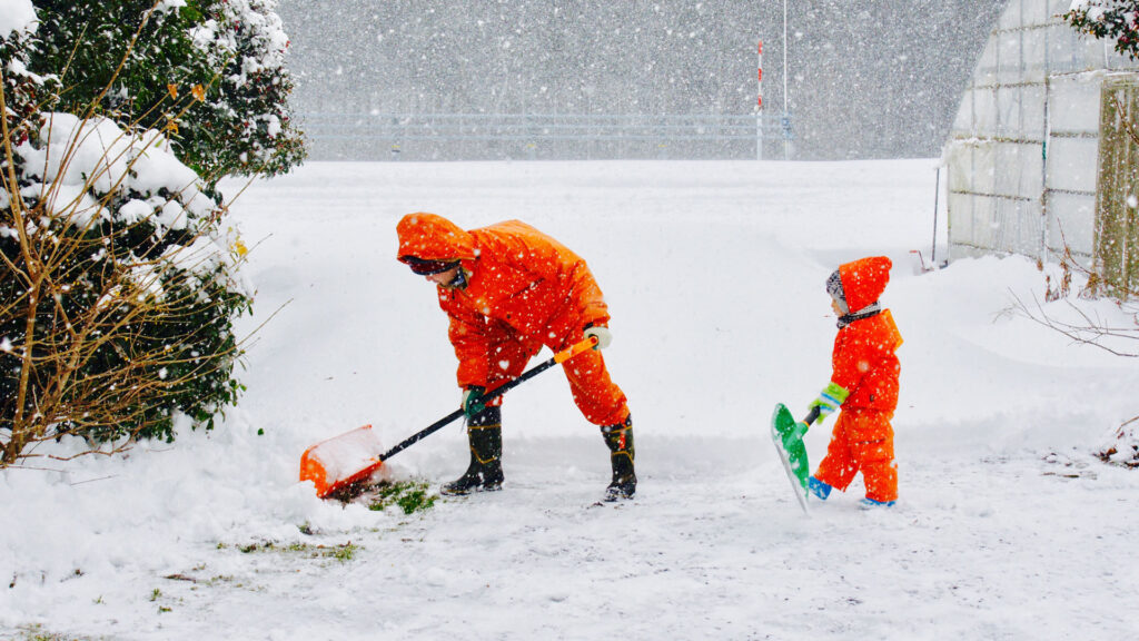 father and son shoveling snow in orange jackets