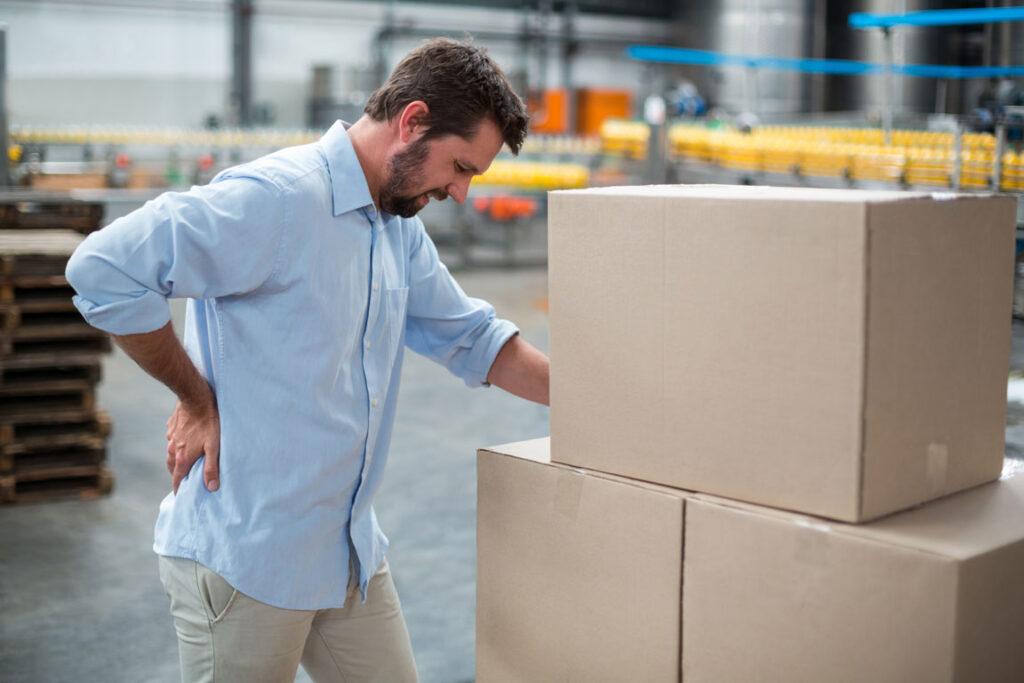 male worker leaning on boxes experiencing back pain