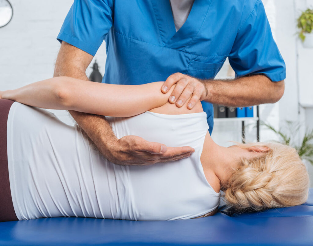 male chiropractor aligning female patient's back