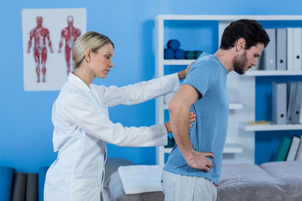 female chiropractor examining male patient's back