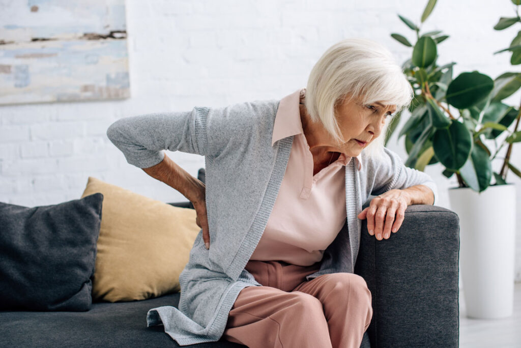 senior woman having back pain on her couch
