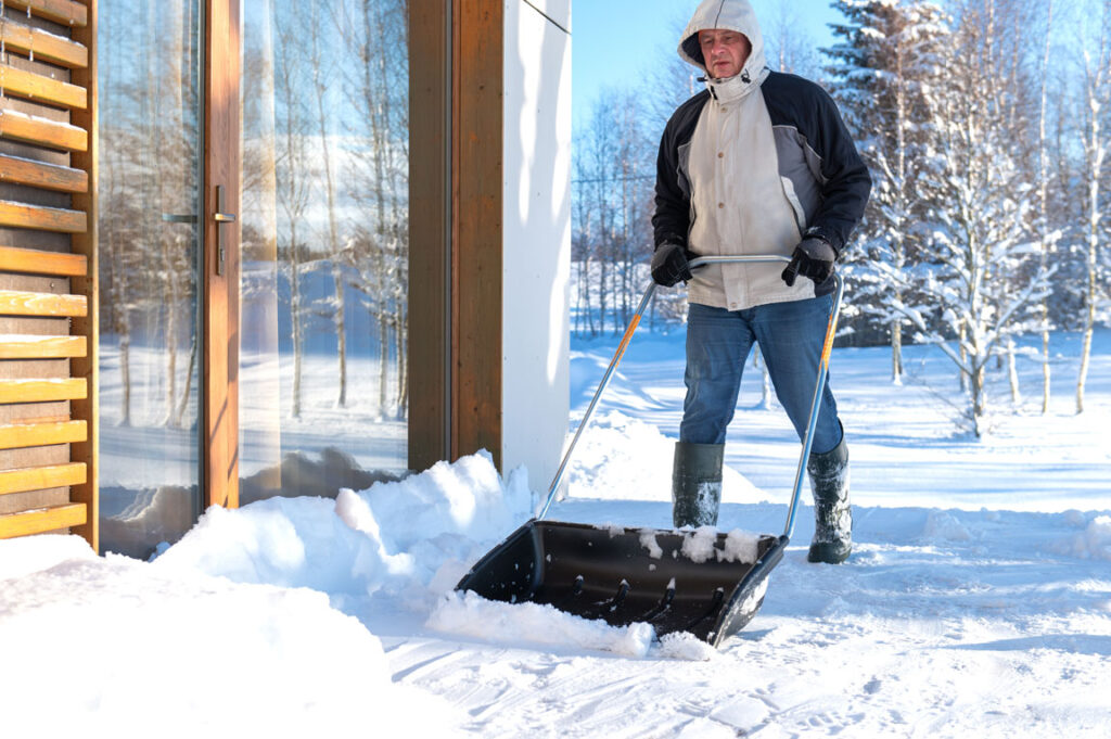 male shoveling snow outside the house