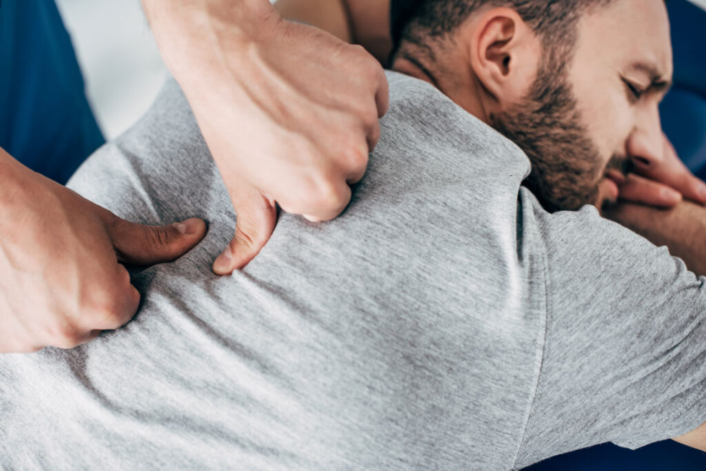 chiropractor massaging male's back