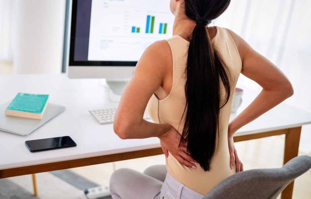 woman sitting at desk with back pain