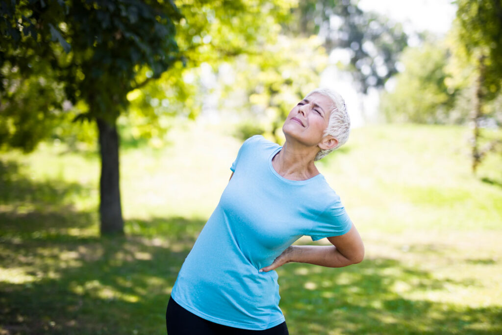 senior woman experiencing back pain outdoors
