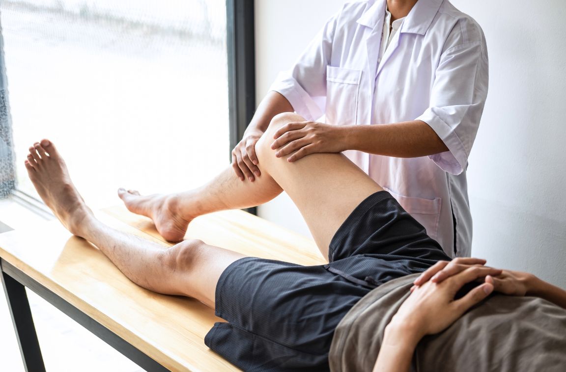 male athlete laying on chiropractic table with bent knee