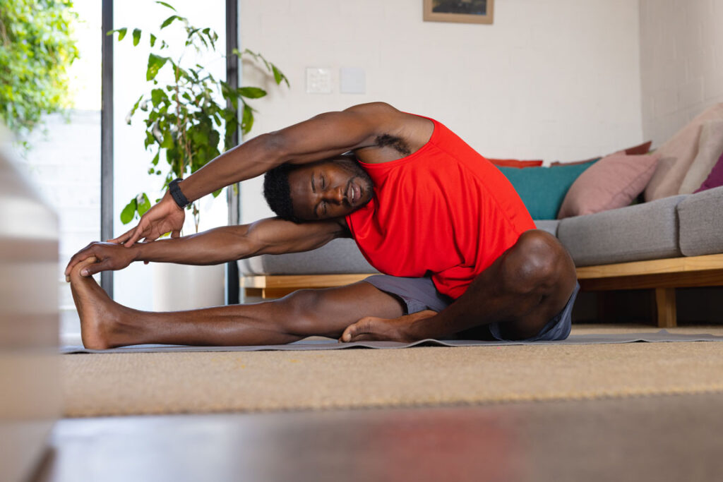 young African American male adult stretching in living room