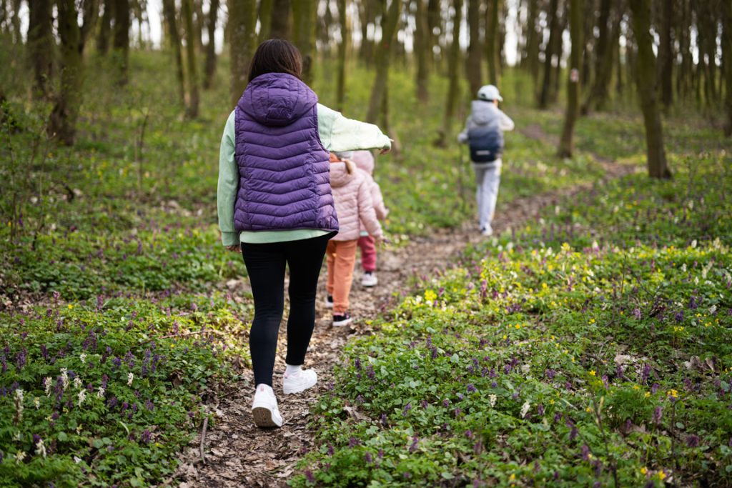 back-view-of-mother-with-three-kids-walking-on family hiking in the woods during the spring