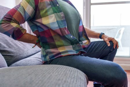 adult with back pain sitting on couch