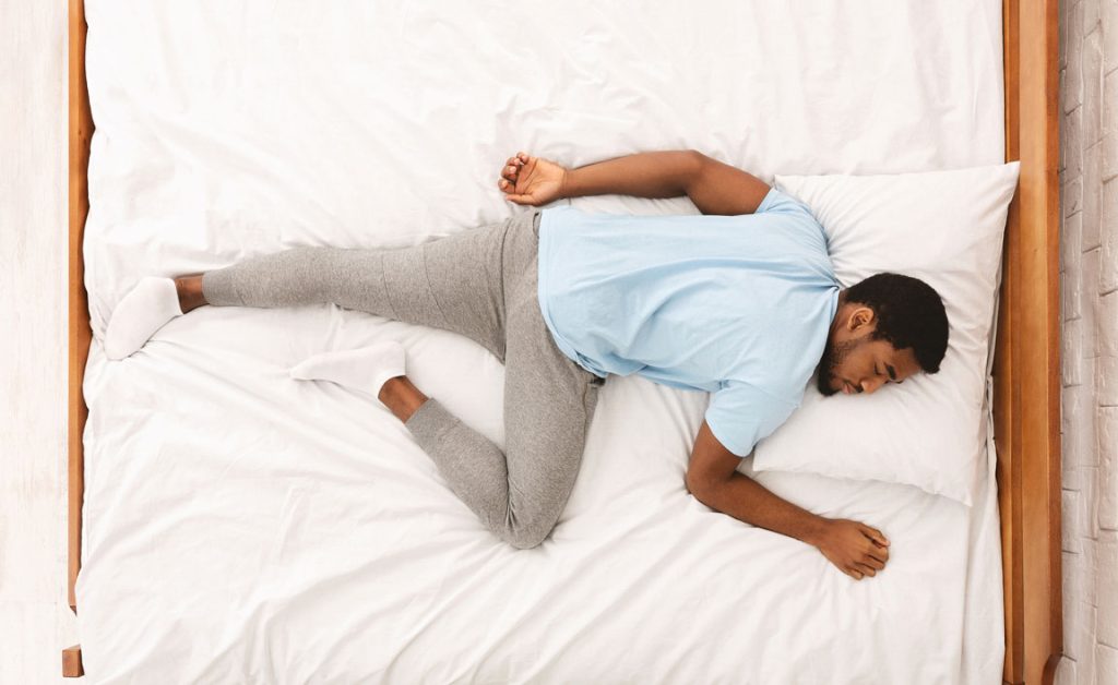 young-african-american-man-sleeping-in-bed-top African American man sleeping in bed with back pain